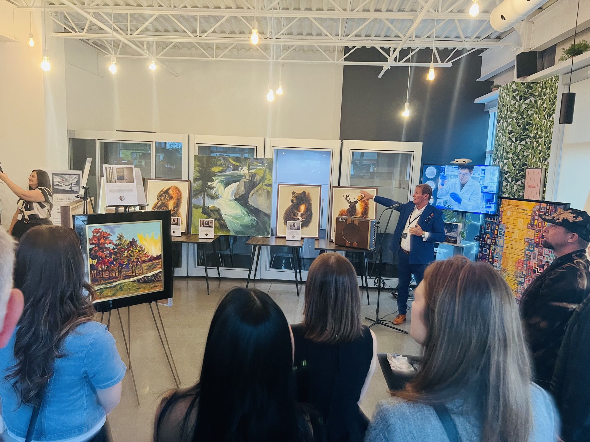 Guests listening to a presentation among paintings