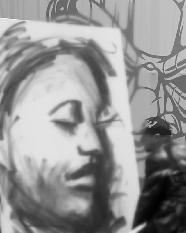 An artist blending charcoal into a large portrait on canvas